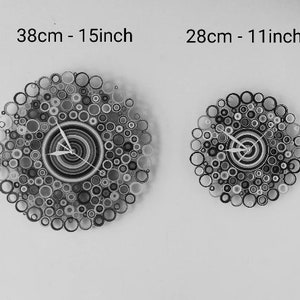 la foto è in bianco e nero e ritrae i due orologi con diametri diversi, il primo è di 38 cm e il secondo è di 28 cm