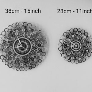 May include: Two black and white paper clocks with a circle design. The larger clock is 15 inches in diameter and the smaller clock is 11 inches in diameter.