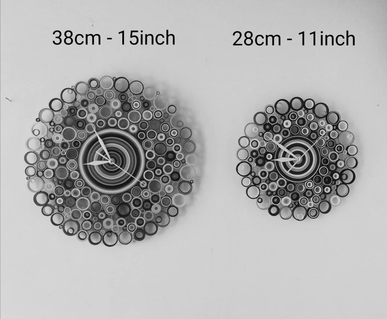 May include: Two black and white paper clocks with a circle design. The larger clock is 15 inches in diameter and the smaller clock is 11 inches in diameter.