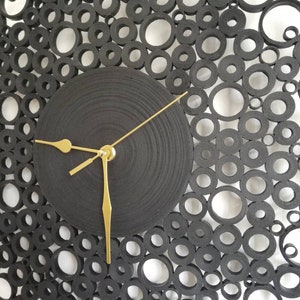 particolare dell'orologio con i rotolini di varie dimensioni e lancette dorate
