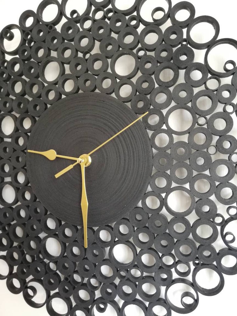 particolare dell'orologio con i rotolini di varie dimensioni e lancette dorate