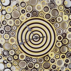 May include: A yellow and brown paper quilled clock with a concentric circle design. The clock face is surrounded by a ring of smaller circles.