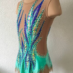 May include: A turquoise leotard with a sheer mesh bodice decorated with blue, purple, and green rhinestones. The leotard has a jagged hemline and a sleeveless design.