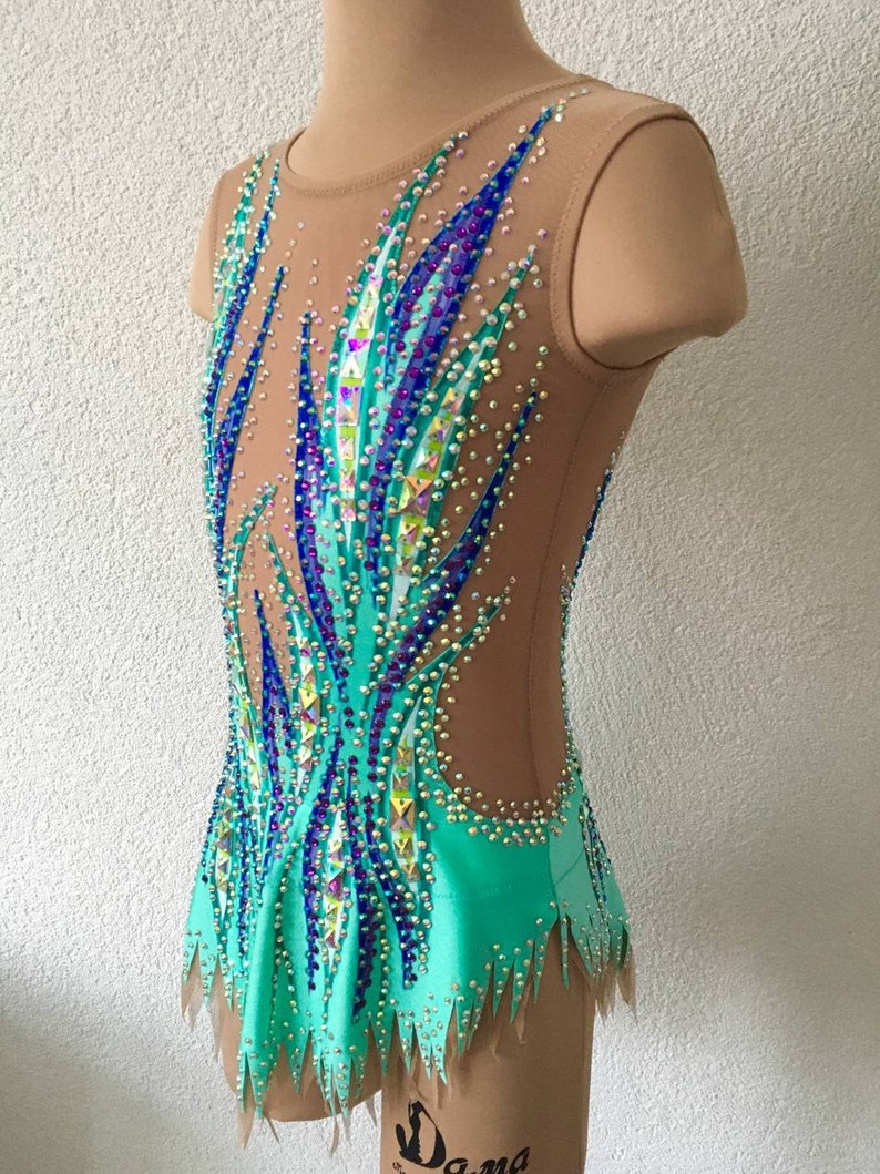 May include: A turquoise leotard with a sheer mesh bodice decorated with blue, purple, and green rhinestones. The leotard has a jagged hemline and a sleeveless design.