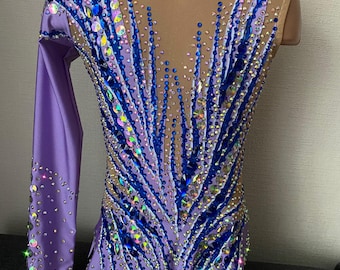 May include: A lilac leotard with long sleeves and a mesh back. The leotard is decorated with blue and iridescent rhinestones in a geometric pattern.