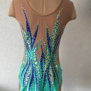 May include: A turquoise leotard with a sheer back and a design of blue and purple rhinestones. The leotard has a scalloped hemline.