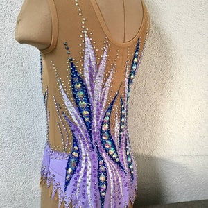 May include: A purple and blue leotard with a geometric design and rhinestones. The leotard has a scoop neck and a sleeveless design.