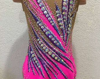 May include: A pink leotard with a brown mesh overlay and a design of purple, blue, and white rhinestones. The leotard has a scalloped hem.
