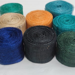 Könnte beinhalten: Eine Sammlung farbenfroher Rollen aus dekorativem Netzband in verschiedenen Farbtönen. Zu den Farben gehören Türkis, Blau, Grün, Orange, Schwarz und Beige. Das Band ist eng gewickelt und bildet eine zylindrische Form. Ideal zum Basteln und Geschenkverpacken.