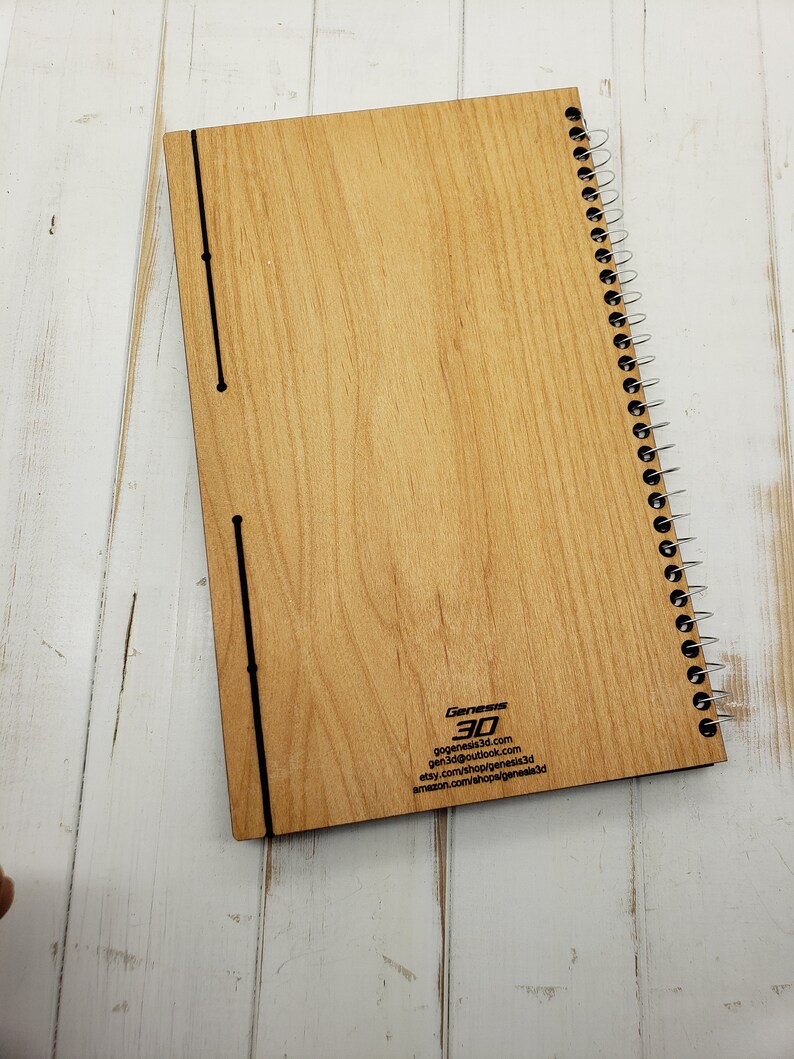 May include: A wooden spiral bound notebook with a wood grain pattern. The back cover has the text "Genesis 3D" and contact information for the company.