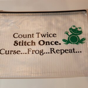 May include: A white mesh zippered pouch with a green frog graphic and the text "Count Twice Stitch Once. Curse...Frog...Repeat..."