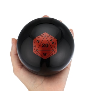 Puede incluir: Una esfera negra con un dado rojo de 20 caras impreso en ella. El dado tiene números negros en cada cara.