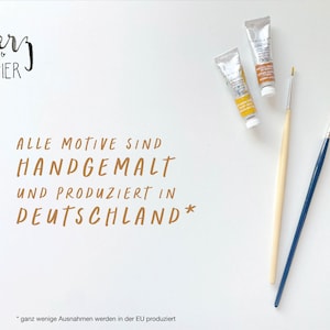 May include: A white background with the text "hevy PAPIER" in black script. The text "ALLE MOTIVE SIND HANDGEMALT UND PRODUZIERT IN DEUTSCHLAND*" is written in brown script. Two tubes of paint and two paintbrushes are on the right side of the image. The text "*ganz wenige Ausnahmen werden in der EU produziert" is at the bottom of the image.