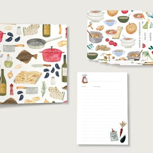 Può includere: Un set di cancelleria illustrata a tema cucina. Include un diario di ricette, schede di ricette e un blocco per appunti. Il diario e le schede presentano un motivo di utensili e ingredienti da cucina. Il blocco per appunti ha un'illustrazione di bilancia e spazio per le note.