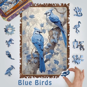 May include: A 500-piece wooden jigsaw puzzle featuring two blue jays perched on a tree branch with green leaves. The puzzle box is also shown in the image, with the title "Blue Birds" on the front.