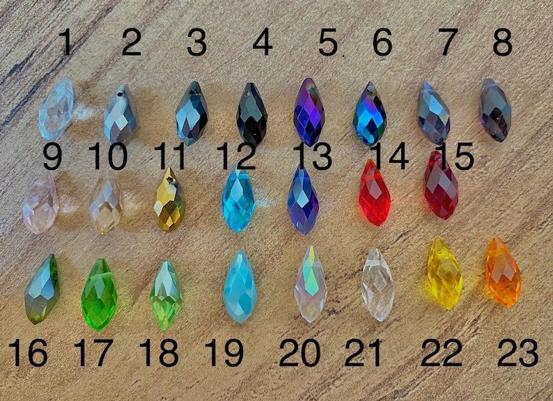 May include: A set of 23 teardrop-shaped crystal beads in various colors, including clear, red, blue, green, and yellow. The beads are numbered 1 through 23.