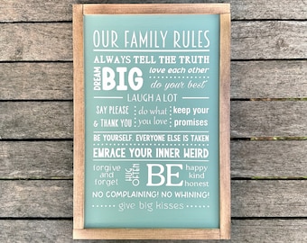 May include: A light blue wooden sign with white text that reads "Our Family Rules" and lists a set of family rules, including "Dream Big", "Laugh a Lot", "Be Yourself", "Embrace Your Inner Weird", "Be Happy, Kind, Honest", "No Complaining! No Whining!" and "Give Big Kisses".