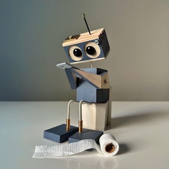 A hand-carved wooden robot caught mid-scroll on the toilet — absurdist bathroom humor meets actual craft skill.