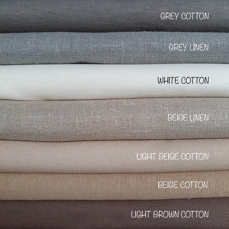 Op de afbeelding: Een stapel van zeven stofstalen in verschillende tinten grijs, beige en bruin. De stalen zijn gelabeld met hun kleur en materiaal, waaronder grijs katoen, grijs linnen, wit katoen, beige linnen, licht beige katoen, beige katoen en lichtbruin katoen.