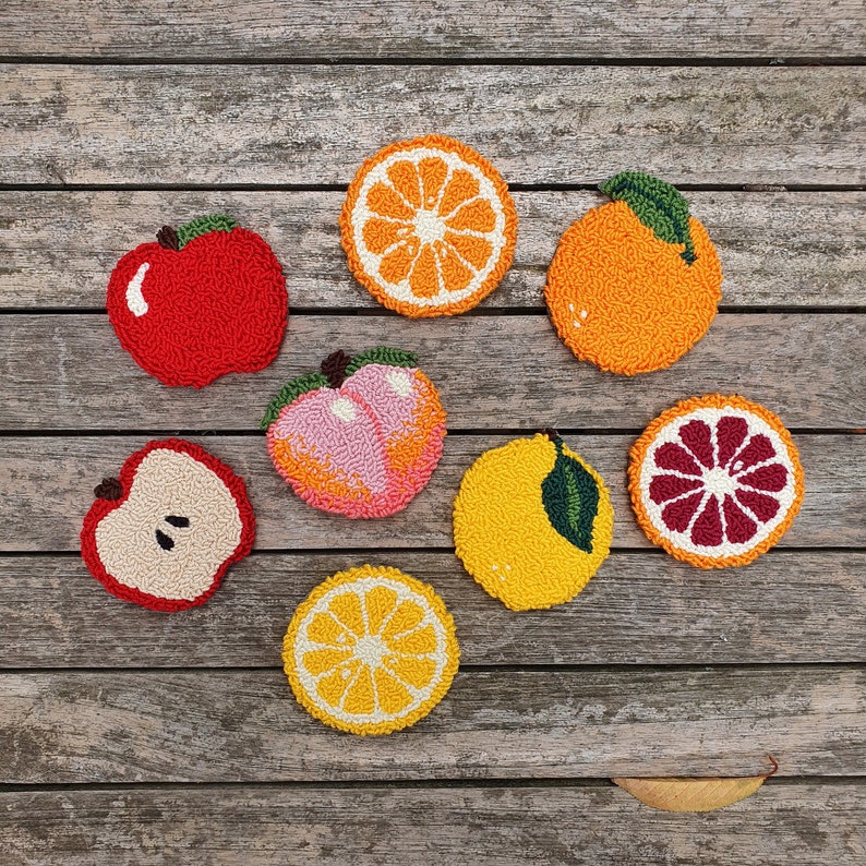 May include: A set of nine felt fruit and citrus ornaments in various colors, including red, orange, yellow, and pink. The ornaments are shaped like apples, oranges, lemons, and peaches.