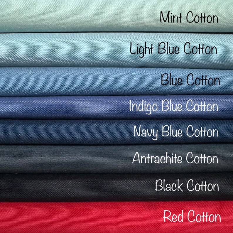 Op de afbeelding: Een stapel van acht stofstalen in verschillende tinten blauw, van lichtblauw tot donkerblauw, met een mintgroen staal bovenaan en een rood staal onderaan. De stalen zijn gelabeld met hun bijbehorende kleuren: Mint Cotton, Light Blue Cotton, Blue Cotton, Indigo Blue Cotton, Navy Blue Cotton, Antrachite Cotton, Black Cotton en Red Cotton.