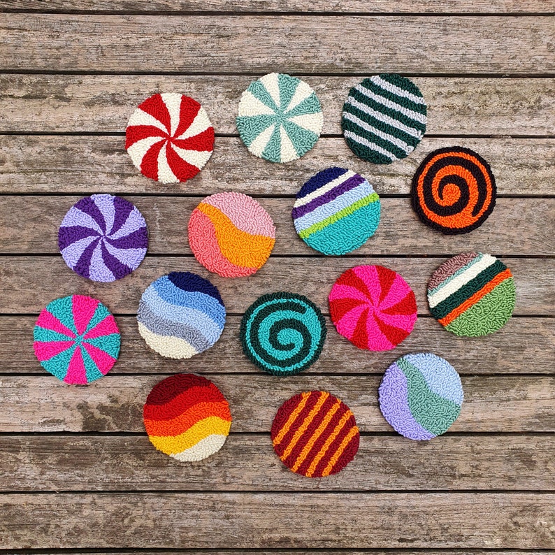 May include: A collection of 15 colorful round crocheted coasters with various patterns, including stripes, swirls, and geometric designs. The coasters are arranged in a circle on a wooden surface.