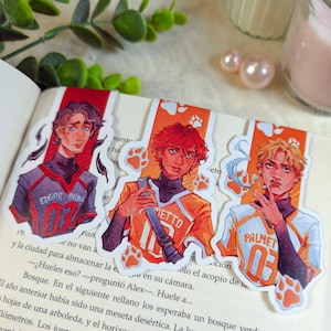 Peut inclure: Trois marque-pages illustrés représentant des jeunes hommes en maillots de sport. Les marque-pages ont un fond blanc avec des empreintes de pattes orange. Le texte sur les maillots indique "EDGAR ALLAN 03", "METTO 10", et "PALMET 03".