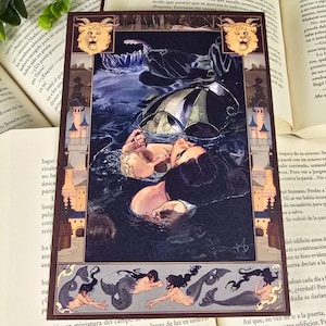 Puede incluir: Una impresión artística de fantasía con una ilustración detallada de figuras en el agua, un paraguas oscuro y sirenas. La impresión tiene un borde decorativo con estructuras tipo castillo y criaturas míticas. La obra de arte se encuentra sobre libros abiertos.