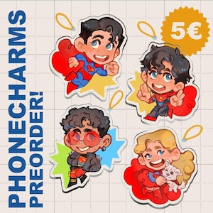 May include: Four cartoon character phone charms with red capes and yellow starburst backgrounds. The charms feature Superman-inspired designs, with one holding a small white dog. The text "PHONECHARMS PREORDER!" is printed vertically on the left.