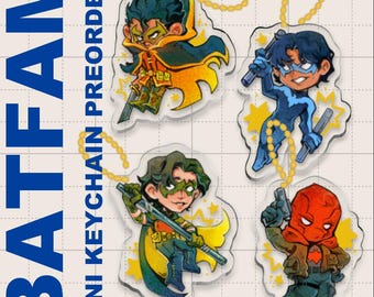 May include: Four mini acrylic keychains featuring comic book characters. Each keychain depicts a different character in a dynamic pose, with vibrant colors and star accents. The keychains are attached to gold-colored beaded chains. Text on the image reads "BATFAM MINI KEYCHAIN PREORDER!"