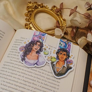 May include: Two illustrated bookmarks featuring a woman with long brown hair and a man with brown hair. The woman is wearing a white dress and the man is wearing a blue shirt and a brown waistcoat. The bookmarks are decorated with a variety of whimsical elements, including a potion bottle, a frog, a doughnut, and a skull.