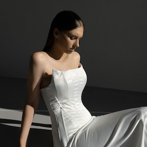 May include: A white strapless gown with a fitted bodice and a flowing skirt.