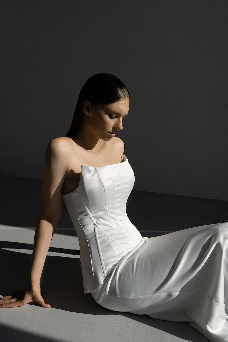 May include: A white strapless gown with a fitted bodice and a flowing skirt.