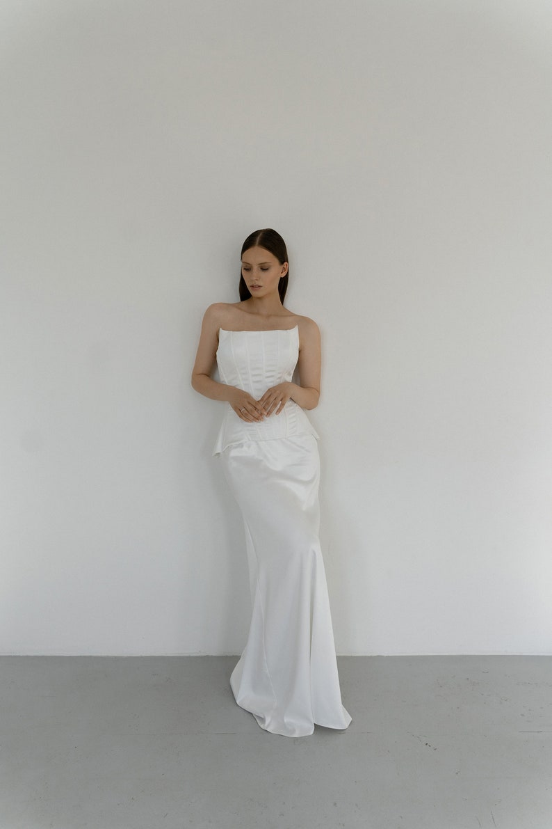 May include: A white strapless wedding dress with a fitted bodice and a flowing skirt.