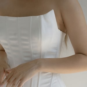 May include: A white strapless corset with vertical seams.