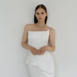 May include: A white strapless dress with a fitted bodice and a flowing skirt.