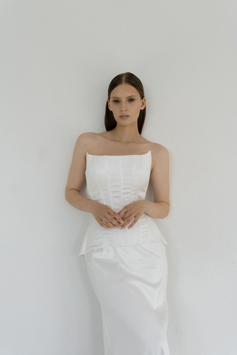 May include: A white strapless dress with a fitted bodice and a flowing skirt.