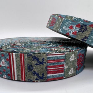 May include: A roll of blue, green, red, and white patterned ribbon with nautical designs, including anchors, sailboats, and steering wheels.