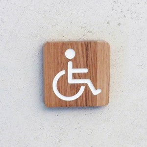 Placa de madeira gravada para indicar acesso para deficientes e PRM