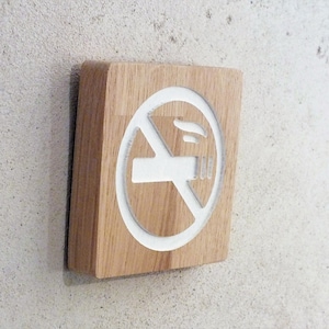 Peut inclure: Un panneau en bois avec un symbole d'interdiction de fumer blanc. Le symbole représente une cigarette avec une ligne diagonale qui la traverse.