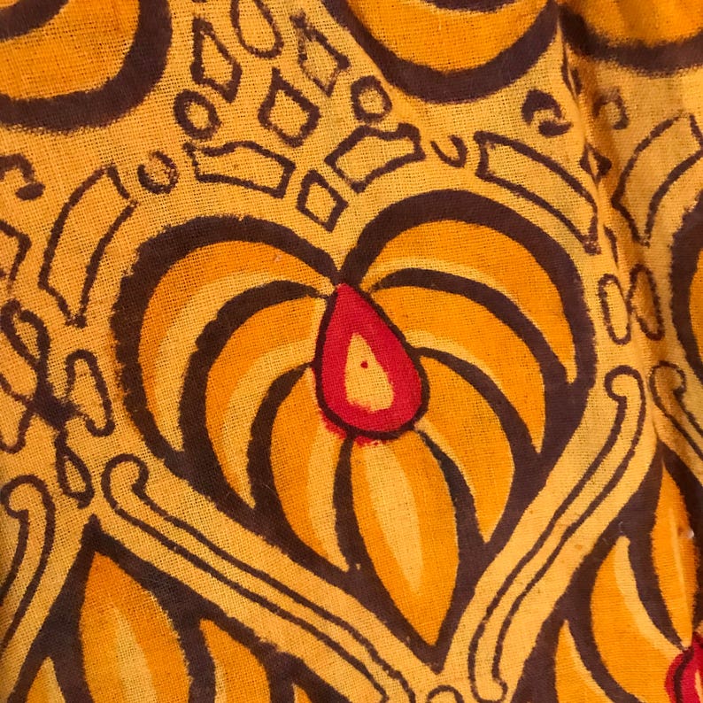 May include: Close-up of a fabric with a brown and yellow pattern. The pattern features a large, stylized flower with a red center.