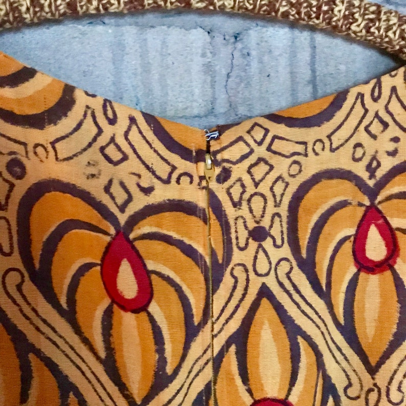 May include: Close-up of the back of a brown and orange dress with a geometric pattern. The dress has a zipper closure in the back.