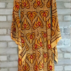 May include: A long, flowing dress with a brown and orange geometric pattern. The dress has a scoop neck and long sleeves. The fabric is sheer and has a vintage feel.
