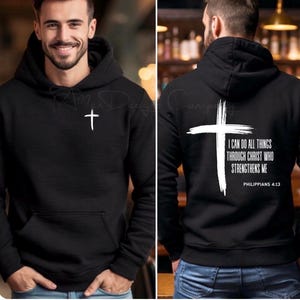 May include: Black hoodie with a white cross on the front and back. The back of the hoodie features the text "I CAN DO ALL THINGS THROUGH CHRIST WHO STRENGTHENS ME" and "PHILIPPIANS 4:13".