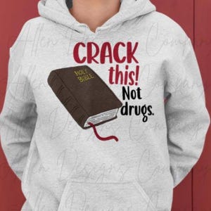 May include: Grey hoodie with the text "CRACK this! Not drugs." and a brown book with the text "HOLY BIBLE" on it.