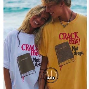 May include: A couple wearing matching t-shirts with the text "CRACK this! Not drugs." and an illustration of a closed book with the text "Holy Bible" on the cover. The man is wearing a yellow shirt and the woman is wearing a white shirt.