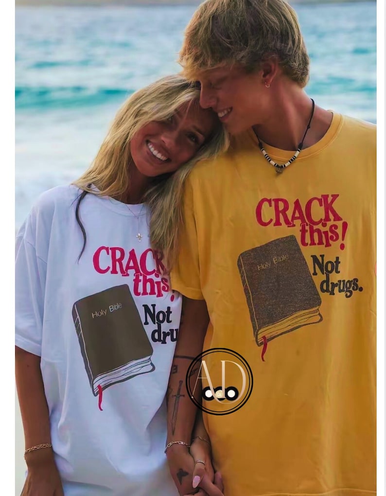 May include: A couple wearing matching t-shirts with the text "CRACK this! Not drugs." and an illustration of a closed book with the text "Holy Bible" on the cover. The man is wearing a yellow shirt and the woman is wearing a white shirt.