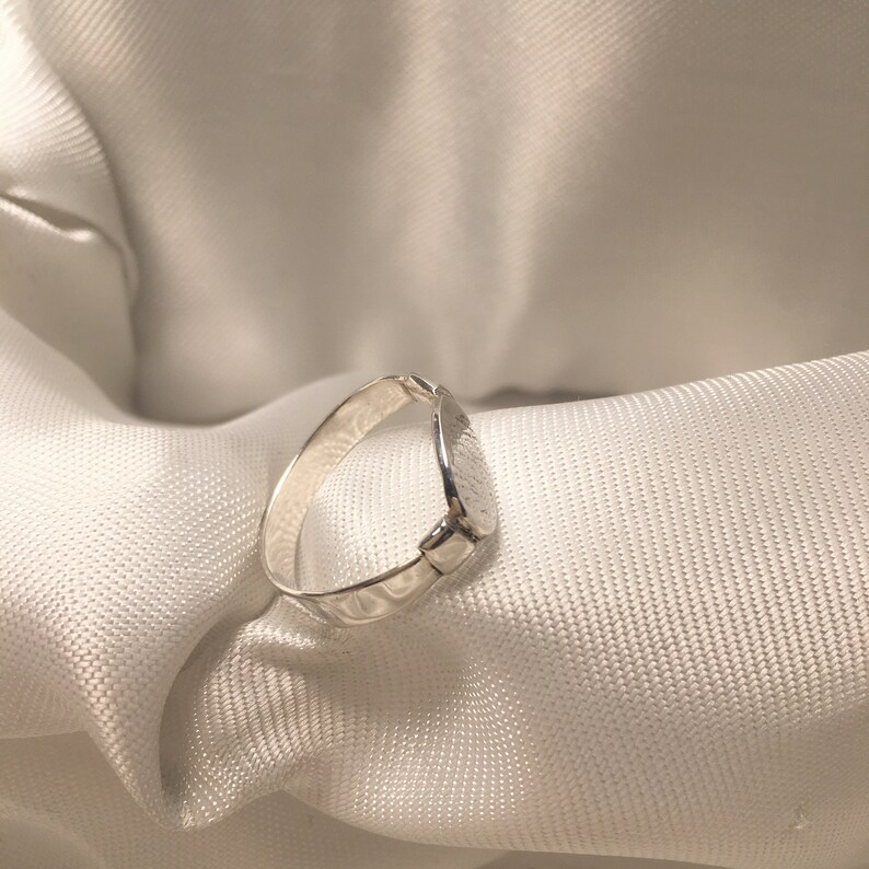 May include: A silver ring with a textured, slightly rounded band.