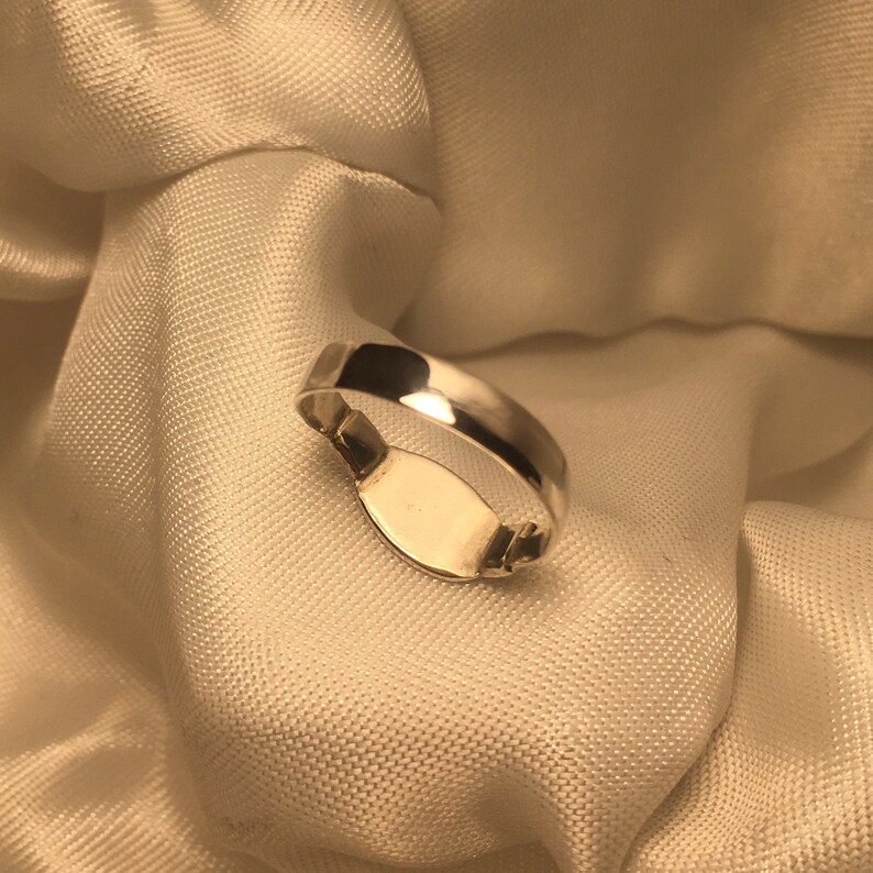 May include: A silver signet ring with a blank oval space for engraving.