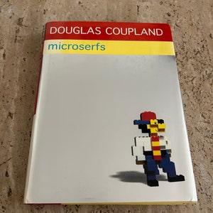 May include: A book cover with a red and yellow background. The title "DOUGLAS COUPLAND" is printed in white on the red band. The title "microsurfs" is printed in blue on the yellow band. A pixelated figure wearing a red hat, white shirt, yellow tie, and blue pants is on the cover.